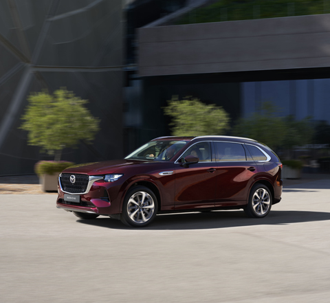 The all wheel drive SUV Mazda CX-80 in red driving in the streets.