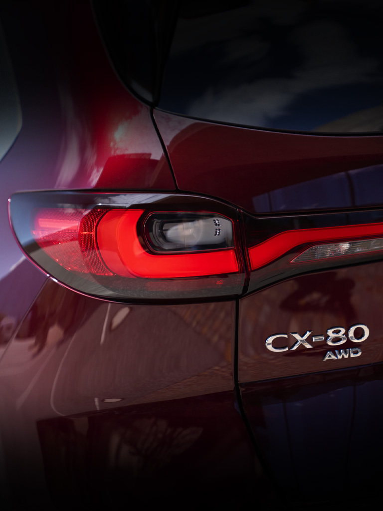 Vista detallada del conjunto de luces traseras del SUV Mazda CX-80, mostrando el diseño con detalles en rojo.