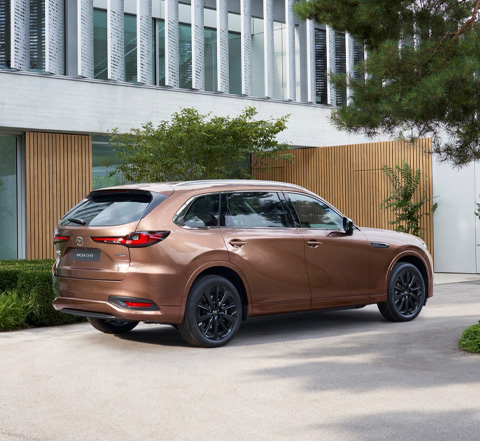 Vue de l’arrière d’un SUV Mazda CX-80 stationné devant une maison.