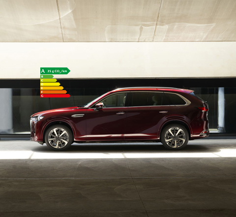 Vue de profil d’un SUV Mazda CX-80 rouge stationné à l’intérieur d’un bâtiment.