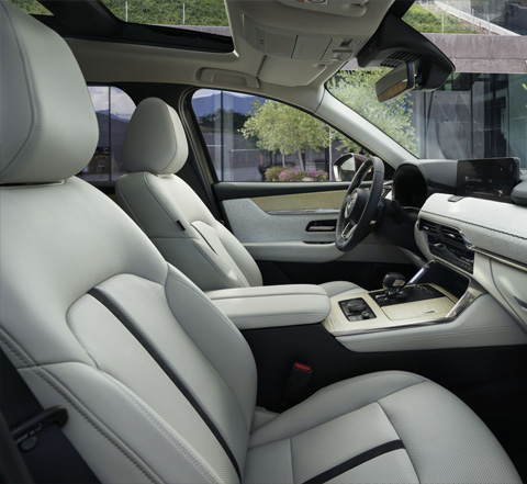 Het interieur van de Mazda CX-80 SUV en zijn comfortabele witte zetels voorin.