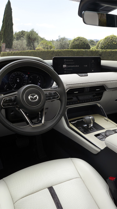 Het stuurwiel met het logo van de Mazda CX-80 en het dashboard met een digitaal weergavescherm.