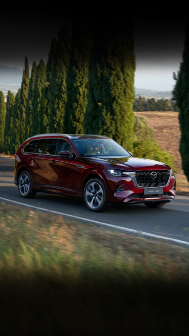 De Mazda CX-80 SUV geparkeerd in een garage met drie mensen die ernaast lopen.