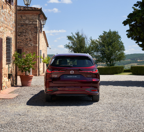 Achterkant van de Mazda CX-80 SUV, geparkeerd voor een huis.