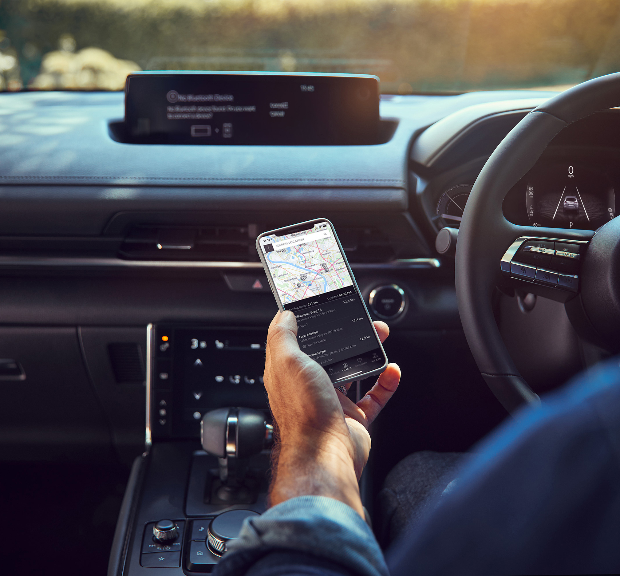 A man holding a smart phone with MyMazda mobile app inside the Mazda MX-30.