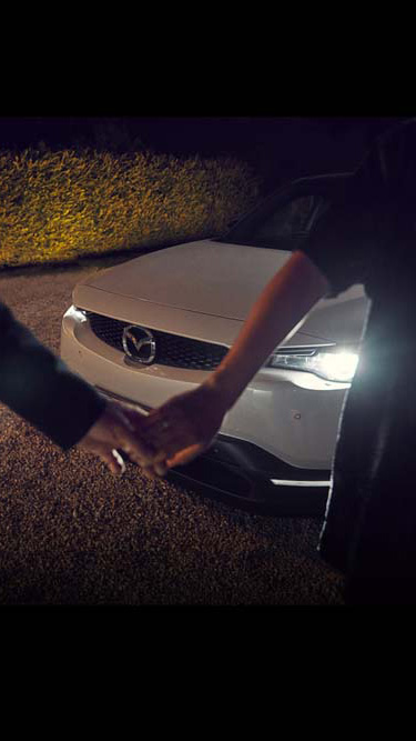 Man and Women holding hands in front of the Mazda MX-30.