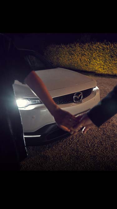Mies ja nainen pitävät toisiaan kädestä Mazda MX-30:n edessä.