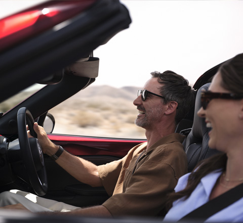 A couple smiles while driving the Mazda MX-5
 Roadster.