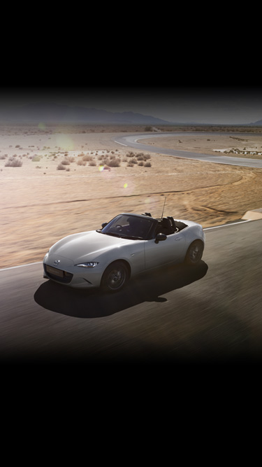 The Mazda MX-5
 driving down a curvy desert road with the top down.