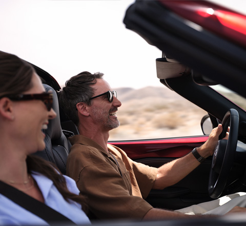 Un couple sourit en roulant à bord de la Mazda MX-5 Roadster.