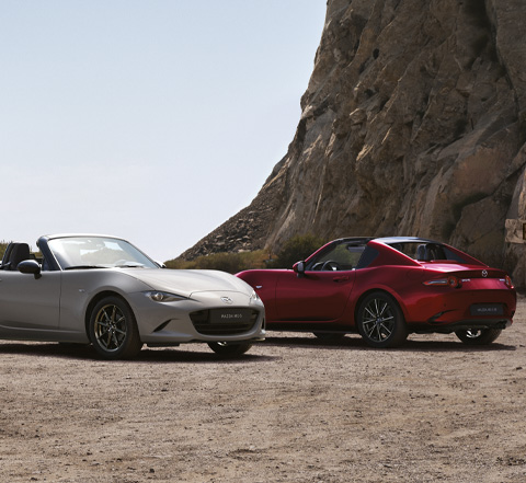 Les Mazda MX-5 Roadster et MX-5 RF garées l'une à côté de l'autre à la plage.