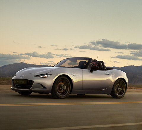 Couple souriant pendant la conduite de la Mazda MX-5
 Roadster.