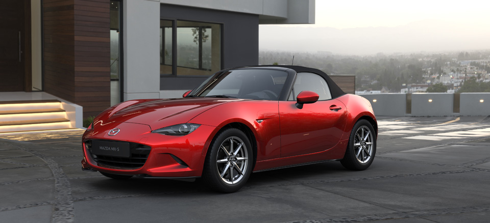 En Mazda MX-5 Roadster parkeret foran et moderne hus.