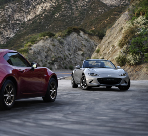 Ein Mazda MX-5 Roadster und ein Mazda MX-5 RF parken einander gegenüber.