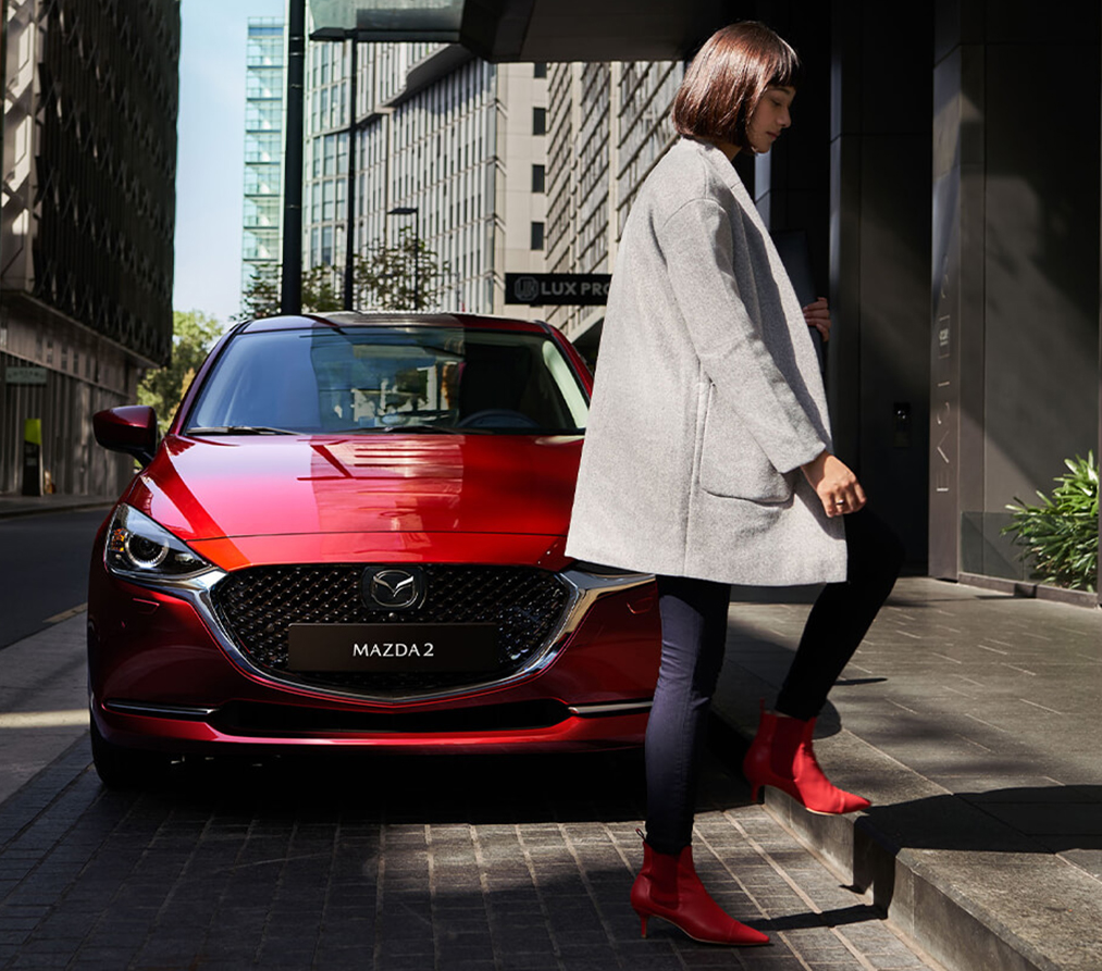 Mazda2 in der Außenfarbe Soul Red Chrystal mit einer Frau
